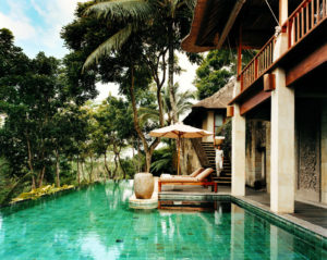 Private pool at the Bayugita residence with view of lounge beds and an assistant walking down the stairs of the residence towards the pool