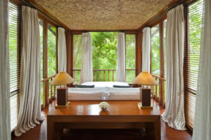 Double bed in one of the bedrooms of the Wanakasa terrace suite with panoramic views of the Bali the jungle out the floor to ceiling windows