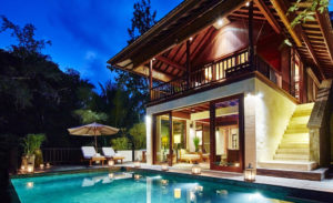 Evening view of the pool at 2 bedroom villa Gesing Kanila with living area and upstairs terrace of the villa behind and lounge beds and parasol next to the pool