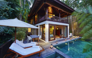 Evening view of the outdoor terrace featuring lounge beds, parasol and pool at the 2 bedroom villa Gesing Kanila with view of the living area and upstairs terrace behind