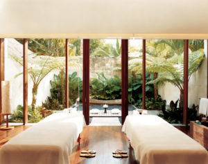 One of Como Shambhala’s treatment rooms with two separate treatment beds and a relaxing tropical garden terrace in the background