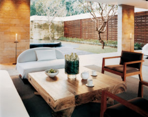 The Ojas lounge with comfortable chairs and tables, a teapot and teacups, and a view of the garden terrace in the background